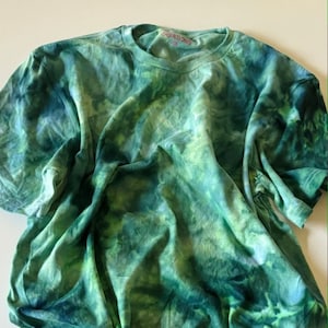 May include: A green tie-dye t-shirt with a white tag that says "CREATIONS" and "M".