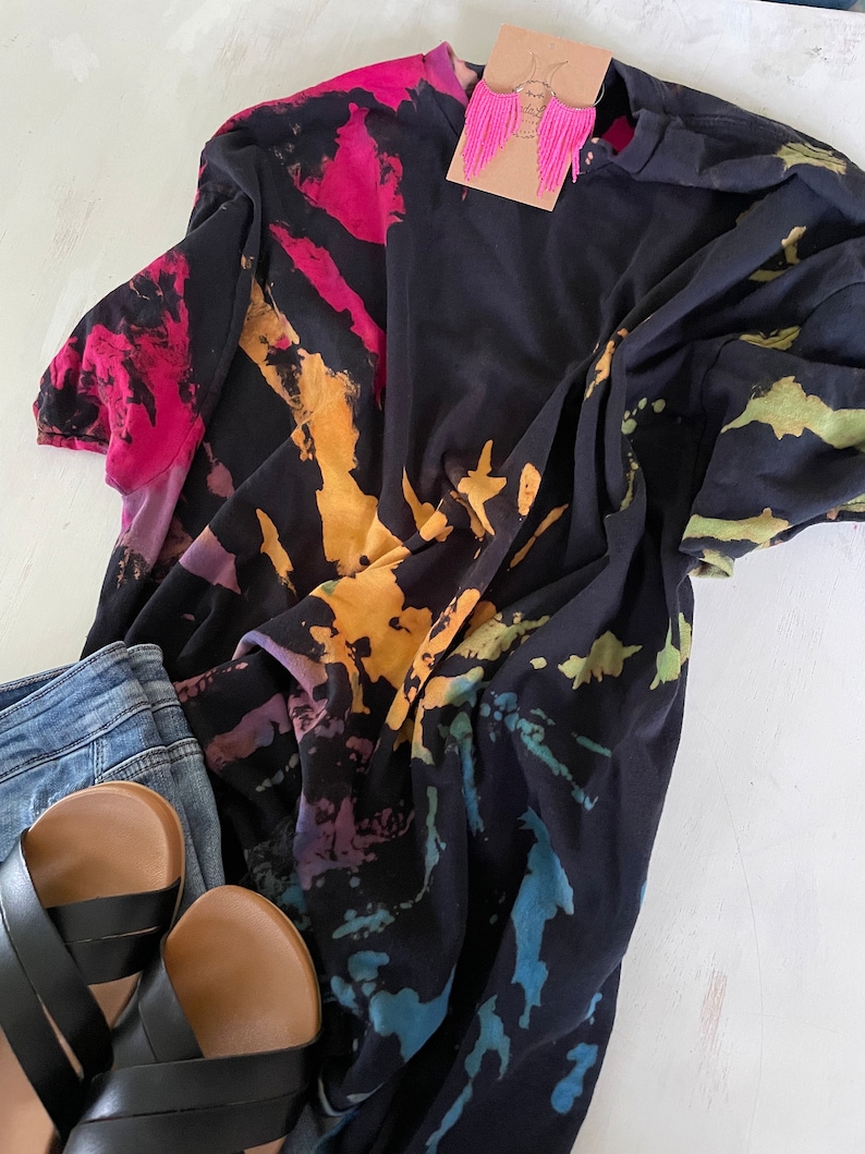 May include: A black tie-dye t-shirt with a colourful swirl pattern. The shirt is made of a soft, comfortable fabric and has a relaxed fit.