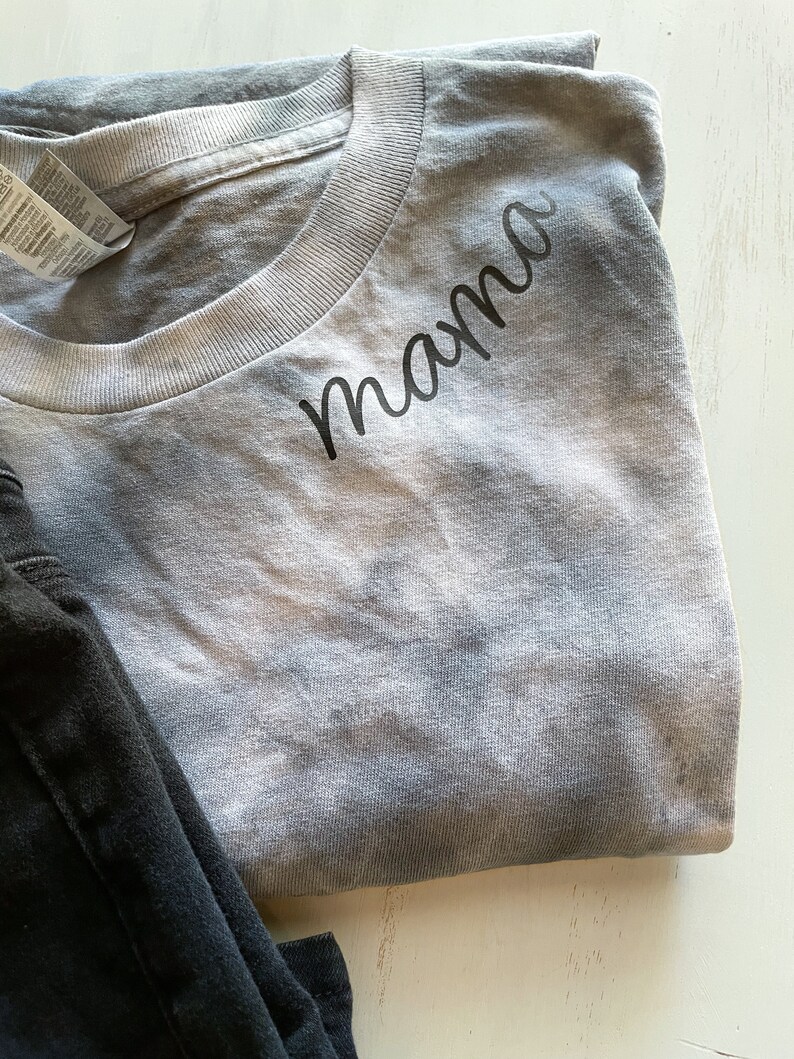 May include: A gray tie-dye t-shirt with the word "mama" written in black cursive on the front.