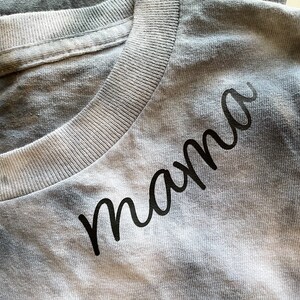May include: A gray t-shirt with the word "mama" written in black cursive script.