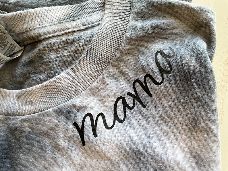 May include: A gray t-shirt with the word "mama" written in black cursive script.