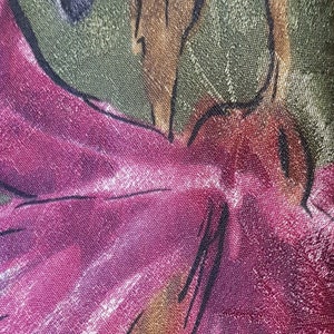 May include: Close-up of a pink floral fabric with a textured surface. The fabric features a large pink flower with a brown stem and green leaves.