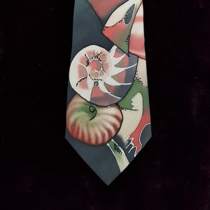 May include: A silk tie with a dark blue background and a colorful abstract design featuring seashells in shades of green, pink, and white.