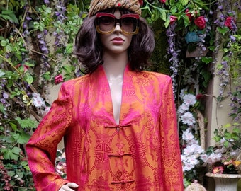 May include: A long, red and orange robe with a traditional Chinese design and multiple buttons. The robe is made of a silky fabric and has a front opening.