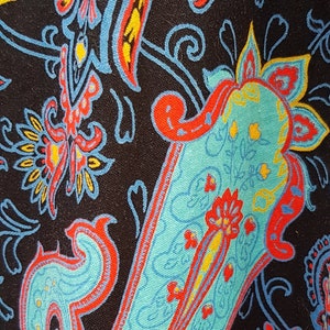 May include: A paisley pattern fabric with a teal, red, yellow, and blue design on a black background.