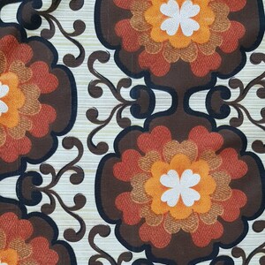 May include: A vintage fabric with a repeating pattern of brown, orange, and white flowers. The background is a light beige with a subtle texture.
