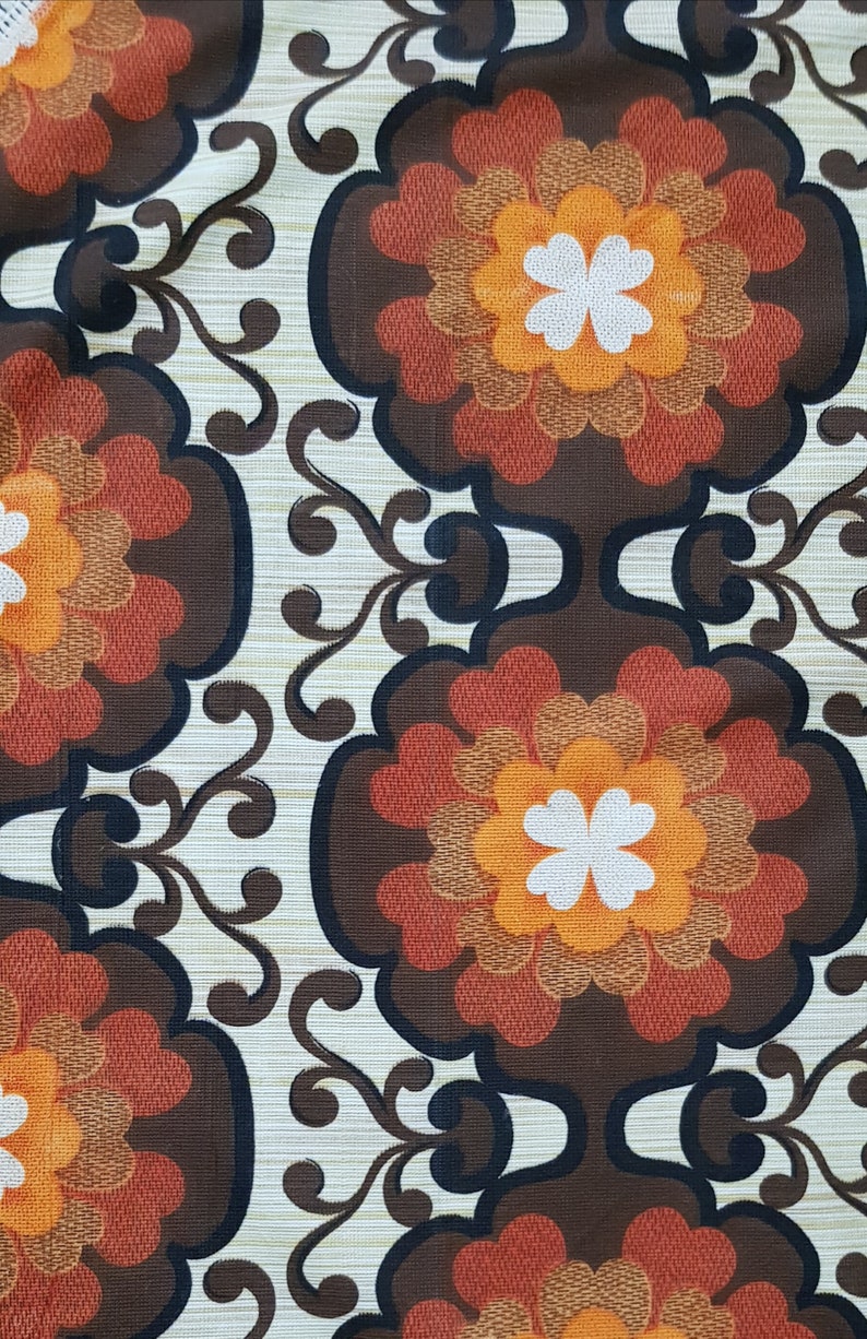 May include: A vintage fabric with a repeating pattern of brown, orange, and white flowers. The background is a light beige with a subtle texture.