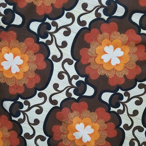 May include: A vintage fabric with a brown, orange, and white floral pattern. The fabric features a repeating design of stylized flowers with a central white clover shape.