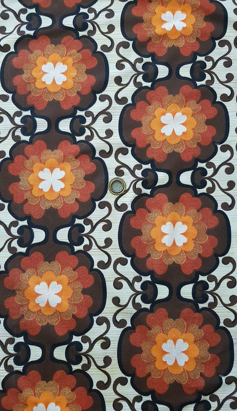 May include: A vintage fabric with a repeating pattern of brown, orange, and white flowers. The fabric has a textured background.