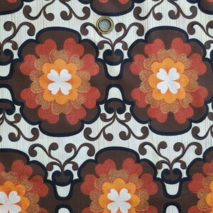 May include: A brown, orange, and white floral pattern fabric with a repeating design. The fabric has a textured surface and a subtle sheen.