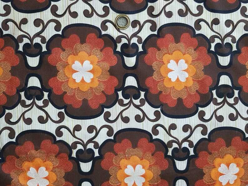 May include: A brown, orange, and white floral pattern fabric with a repeating design. The fabric has a textured surface and a subtle sheen.