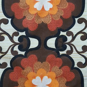 May include: A vintage fabric with a repeating pattern of brown, orange, and red flowers with white centers. The background is a light beige with a subtle texture.