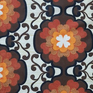 May include: A vintage fabric with a repeating pattern of brown, orange, and white flowers. The flowers have a multi-layered design with a white center and are surrounded by a brown background.