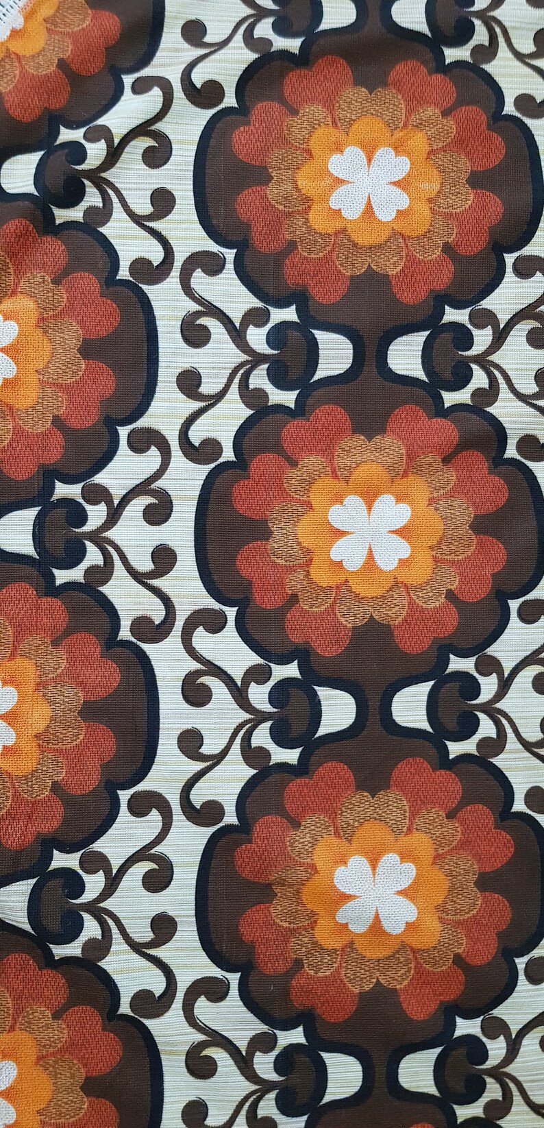 May include: A vintage fabric with a repeating pattern of brown, orange, and white flowers. The flowers have a multi-layered design with a white center and are surrounded by a brown background.