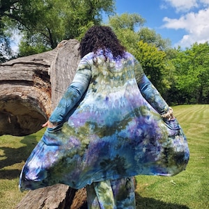 May include: A long, flowing tie-dye cardigan in shades of blue, green, and purple. The cardigan is made of a soft, comfortable fabric and has a relaxed fit.