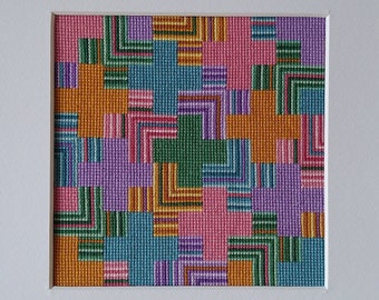 May include: A framed artwork featuring a geometric pattern of squares in shades of orange, pink, purple, green, and blue. The squares are arranged in a repeating pattern, creating a visually interesting and abstract design.
