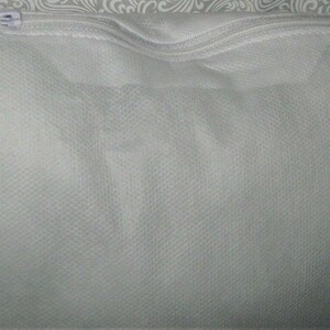 May include: A white zippered pouch made of a soft, textured fabric. The pouch is empty and appears to be made of a breathable material.