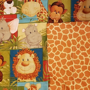 Op de afbeelding: Een kleurrijk patchwork-deken met verschillende jungledieren, waaronder een leeuw, een giraffe, een olifant, een aap, een tijger en een nijlpaard. Het deken is gemaakt van een zachte, gestikte stof en heeft een bruine en oranje giraffenprint aan de achterkant.