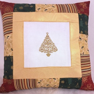May include: A gold embroidered Christmas tree design on a white pillow with a gold and red patchwork fabric cover.