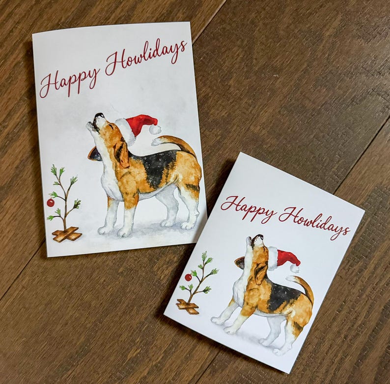 May include: Two white greeting cards with the text "Happy Howlidays" in red script. Each card features a watercolor illustration of a beagle wearing a Santa hat and howling. A small Christmas tree is also depicted.