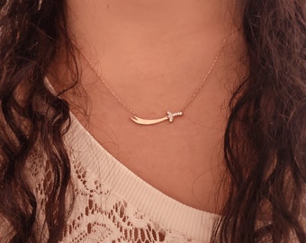 May include: A gold necklace with a diamond-encrusted sword pendant.