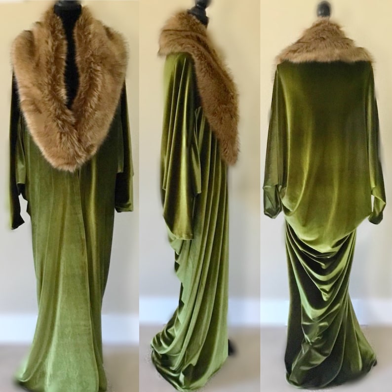 Puede incluir: Una larga t&uacute;nica de terciopelo verde con un cuello de piel marr&oacute;n. La t&uacute;nica tiene un dise&ntilde;o fluido y drapeado y se muestra en un maniqu&iacute;.