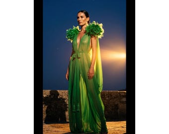 May include: A floor-length, sheer green dress featuring a deep V-neckline, a tie-waist belt with tassels, and voluminous green feather accents on the shoulders. The garment is crafted from a lightweight, translucent fabric that drapes to the floor.