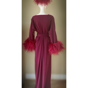 May include: A long, burgundy robe with long sleeves and a sash. The sleeves and hat are trimmed with burgundy feathers.