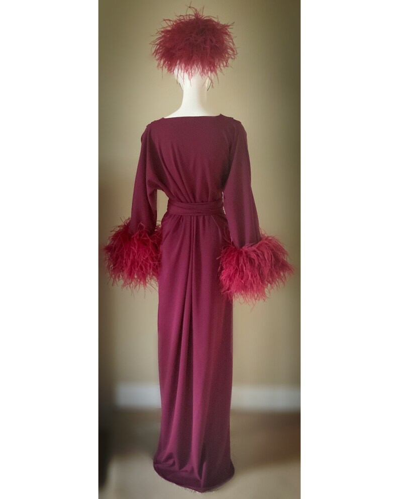 May include: A long, burgundy robe with long sleeves and a sash. The sleeves and hat are trimmed with burgundy feathers.