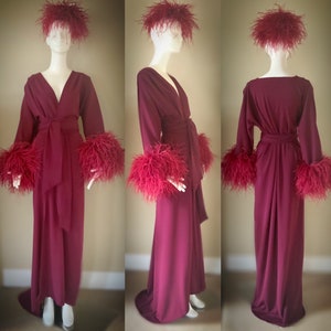 May include: A long, burgundy robe with feather trim on the cuffs and collar. The robe has a wrap style and a sash tie at the waist.