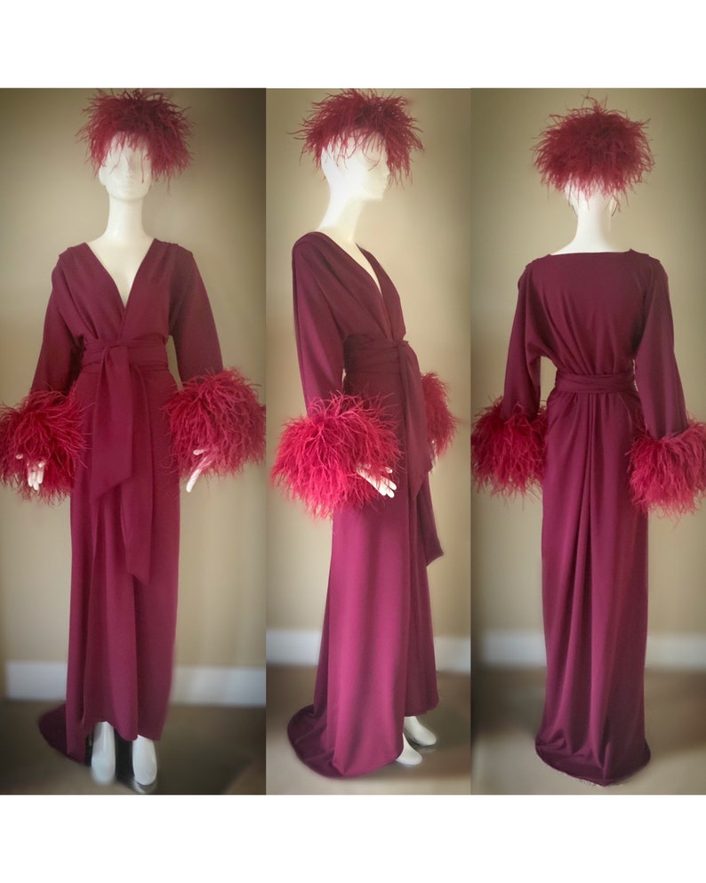 May include: A long, burgundy robe with feather trim on the cuffs and collar. The robe has a wrap style and a sash tie at the waist.