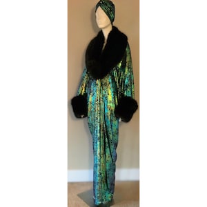 May include: A long, green and gold iridescent robe with black fur trim around the collar and cuffs. The robe is worn on a mannequin with a black turban.