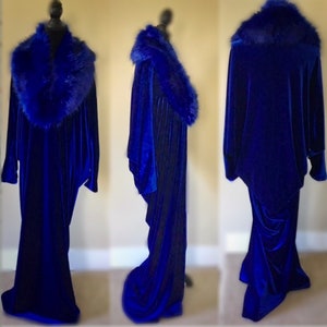 May include: A royal blue velvet gown with a faux fur collar. The long-sleeved dress has a flowing silhouette and is displayed on a mannequin. The faux fur collar is a deep blue color, complementing the velvet fabric.