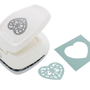 May include: White paper punch with a heart-shaped design. The punch is open and shows the heart-shaped cut-out. A sample of the cut-out is shown in light blue paper.