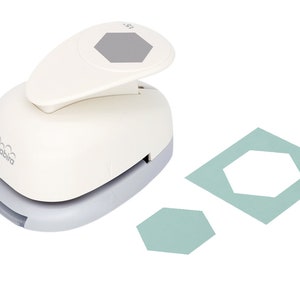 May include: White paper punch with a gray hexagon shape on the top. The punch is on a white surface with two teal hexagon shapes punched out of paper.