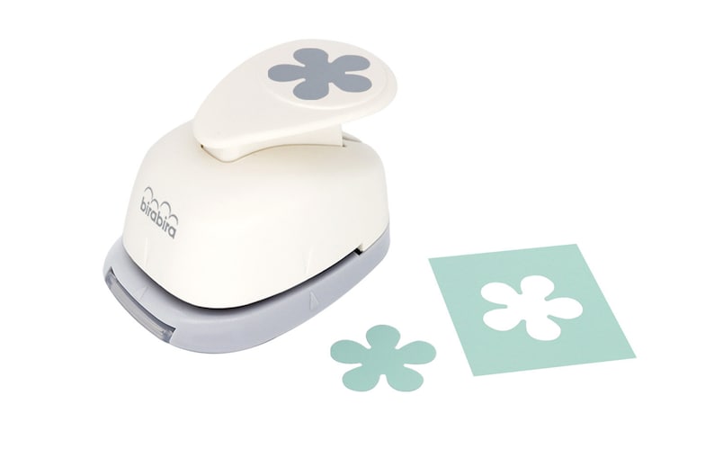 May include: A white paper punch with a gray flower design on the top. The punch is used to create paper flowers. The image shows the punch, a paper flower, and a piece of paper with a flower cut out.