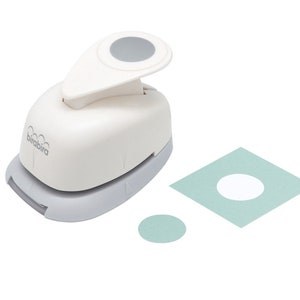 Op de afbeelding: Een witte en grijze cirkelpons met een grijze handgreep. De pons staat op een wit oppervlak met een lichtblauwe cirkel en een lichtblauw vierkant met een uitgesneden witte cirkel.