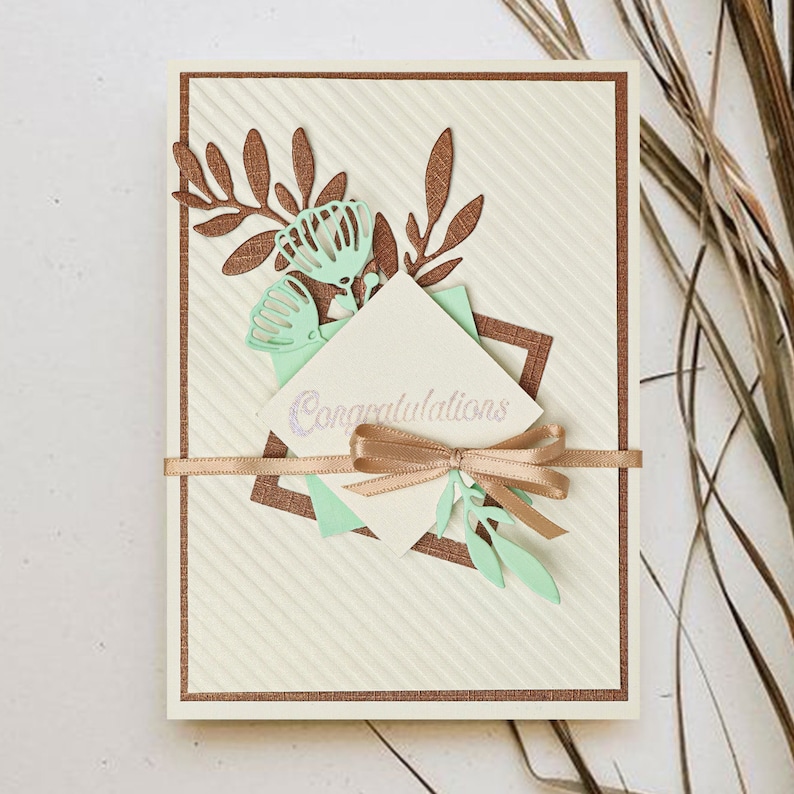 May include: A white card with a brown border and a green and brown floral design. The card has a white envelope with the word "Congratulations" written on it.