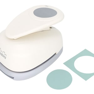 May include: White circle punch with a gray handle and a gray circle on the top. The punch is on a white background with two samples of circles punched from paper. One circle is on a white background and the other is on a light blue background.