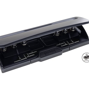 May include: A black and gray hole punch with a yellow lever. The hole punch has three sets of hole punches and can punch up to 8 sheets. The hole punch has the words "A5", "Personal Deskfax", "Pocket Mini", and "A6 Agenda" printed on it.