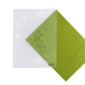 Peut inclure: Un dossier de gaufrage en plastique transparent avec un motif floral de roses et de feuilles. Le dossier est présenté avec une feuille de papier cartonné vert gaufrée avec le même motif.