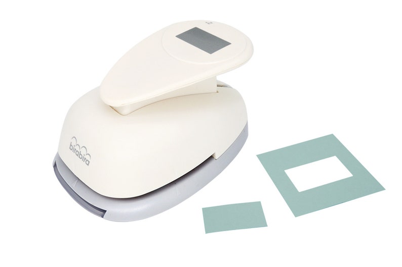 May include: White paper punch with a grey base and a digital display. The punch is used to create a rectangular hole in paper. Two samples of punched paper are shown, one with a larger rectangle and one with a smaller rectangle.
