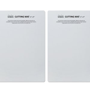May include: Two grey cutting mats with the text "birabira CUTTING MAT 6" x 9" printed on them. Use the front and back side interchangeably. Different placement of compatible tools on the mat when cutting & embossing for longer duration. Inappropriate use will shorten the product life.