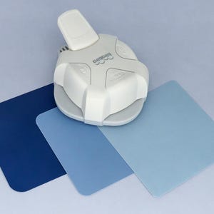 May include: A white paper punch with a blue, light blue, and dark blue paper samples. The punch has a lever and a circular cutting area. The paper samples are squares.