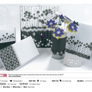 May include: A black and white card with a floral design. The card is decorated with a black and white ribbon and a black and white flower. The card is surrounded by other black and white cards and a black and white vase with a flower arrangement.