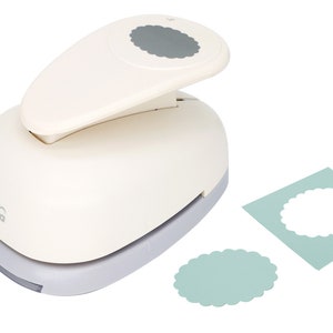May include: A white paper punch with a gray handle and a scalloped circle design. The punch is on a white background with two samples of the punched design in light blue.