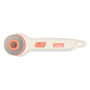 May include: A white rotary cutter with a coral safety button and blade housing. The silver, circular blade is visible. The handle features the brand name "birabira" in coral. This tool is used for cutting fabric and paper.