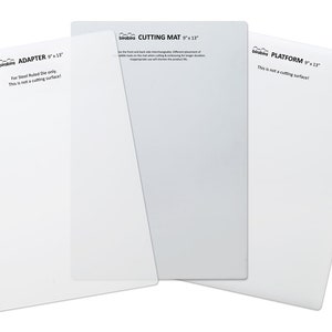 May include: Three white cutting mats for a craft machine. The mats are labeled "ADAPTER 9" x 13", "CUTTING MAT 9" x 13", and "PLATFORM 9" x 13".