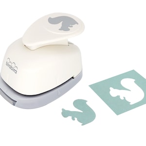 May include: White plastic squirrel punch with a gray handle. The punch is used to create a squirrel shape from paper. A blue paper square with a white squirrel cutout is shown next to the punch. A white squirrel cutout is also shown on the white surface.