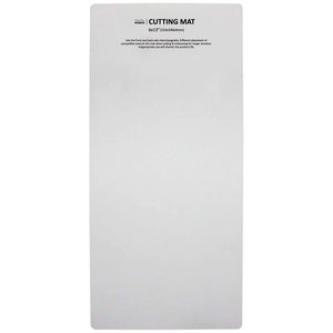 May include: A white rectangular cutting mat with the text "CUTTING MAT" and dimensions of 6x13 inches. The mat has additional text about using the front and back sides interchangeably. The mat is designed for cutting and embossing.